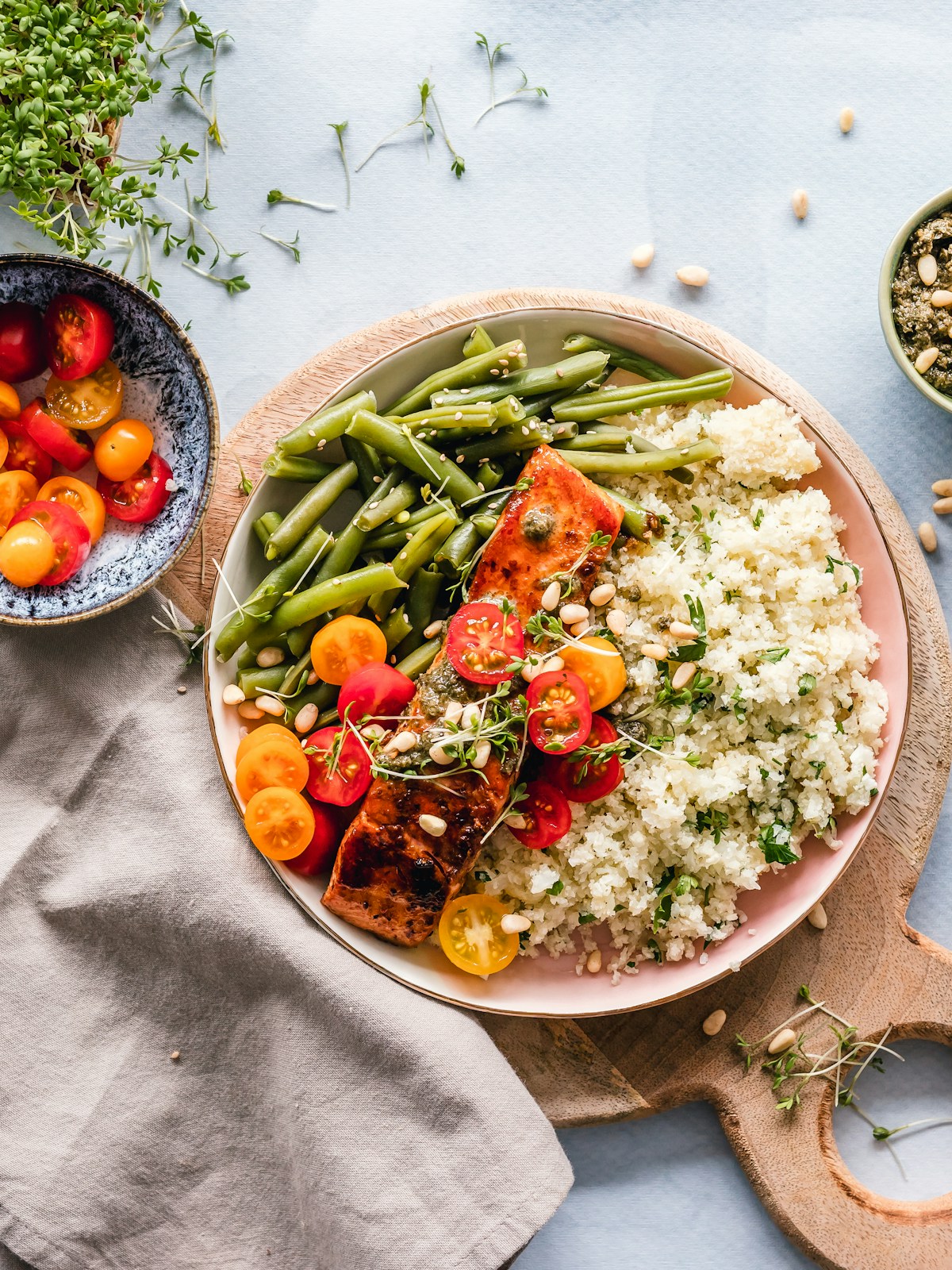 Vakkert servert nordisk måltid med laks, friske grønnsaker og urter på keramisk tallerken, naturlig lys